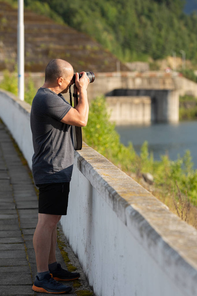 Middle aged male photographer with professional camera taking pictures outdoor at daytime - Valokuva, kuva