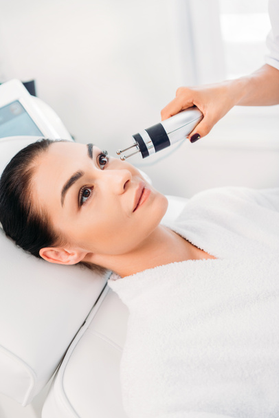 attractive woman getting facial microcurrent therapy in spa salon - Fotó, kép