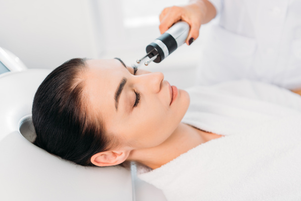 Attractive woman getting facial microcurrent therapy in spa salon - Фото, зображення