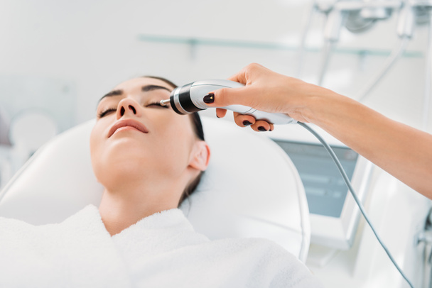 atractiva mujer recibiendo terapia de microcorriente facial en el salón de spa
 - Foto, Imagen