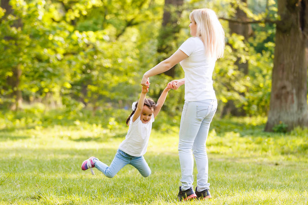 Mutter und Tochter spielen im grünen Park im Kreis - Foto, Bild