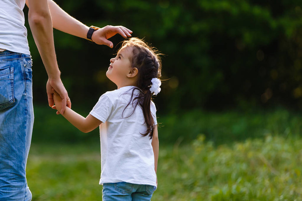 Очаровательная маленькая девочка держит своего отца за руку - Фото, изображение