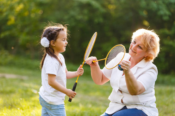 Grandmother and her little granddaughter playing tennis outdoors - Fotó, kép