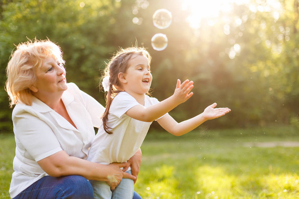 bambina soffiando bolle di sapone con la nonna all'aperto
 - Foto, immagini