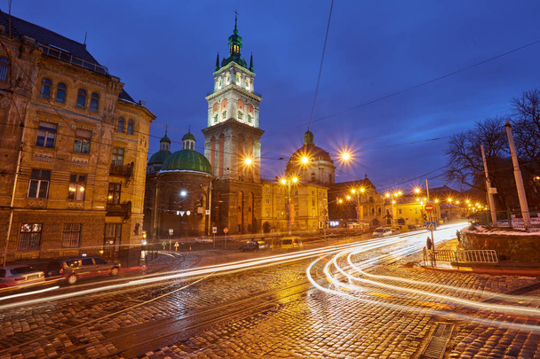 ヴィンテージの夕暮れに照らされた仮定教会鐘楼を眺め前景、リヴィウ、ウクライナをトラムが走る。冬の夜の風景. - 写真・画像