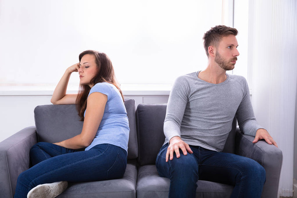 Upset Young Couple Sitting On Sofa At Home - Foto, Imagen
