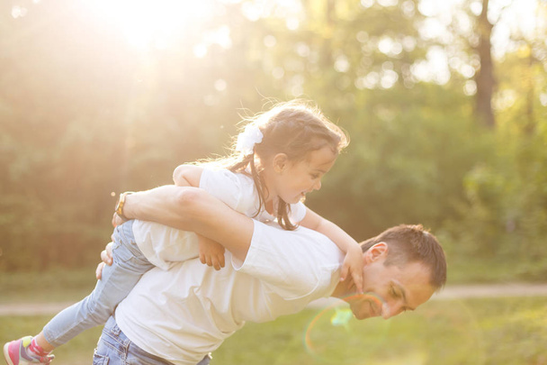 junger Vater trägt Mädchen auf dem Rücken kleine Tochter - Foto, Bild