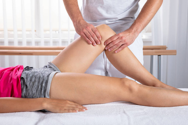 Woman Receiving Knee Massage By Male Therapist - Foto, imagen