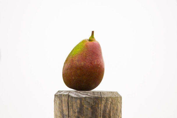 a ripe pear stands isolated on a wooden post against a white background - Foto, Bild