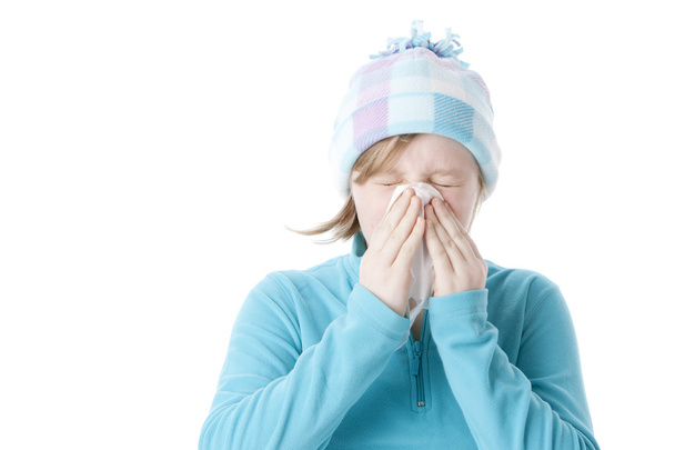 Little girl sneezing and blowing her nose with a cold and flu - Foto, Bild