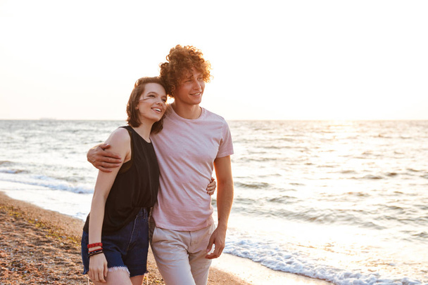 Image of cute young happy loving couple hugging outdoors on the beach. - Φωτογραφία, εικόνα