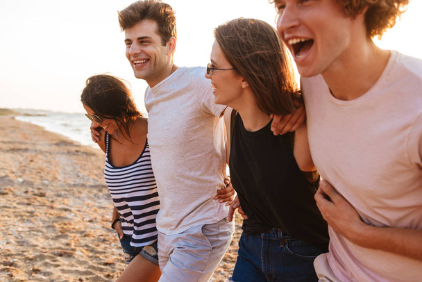 Image of excited group of friends loving couples walking outdoors on the beach having fun. - Zdjęcie, obraz
