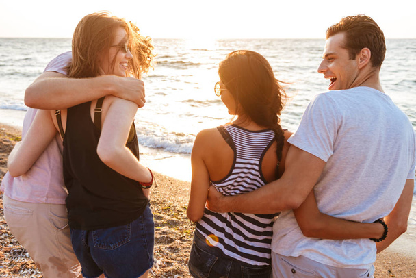 Image of excited group of friends loving couples walking outdoors on the beach having fun. - Foto, imagen