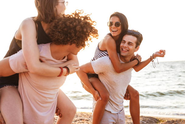 Picture of happy group of friends loving couples walking outdoors on the beach having fun. - Valokuva, kuva