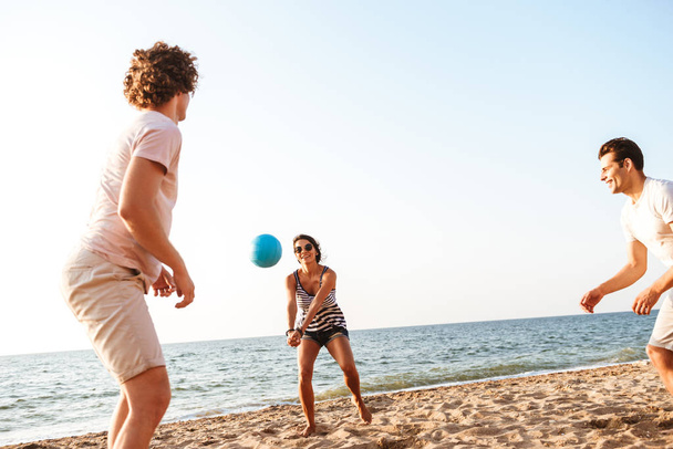 Foto de amigos felices al aire libre en la playa jugar voleibol divertirse
. - Foto, imagen
