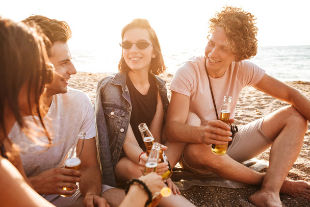 Group of excited young friends having fun time together at the beach, drinking beer - Фото, изображение