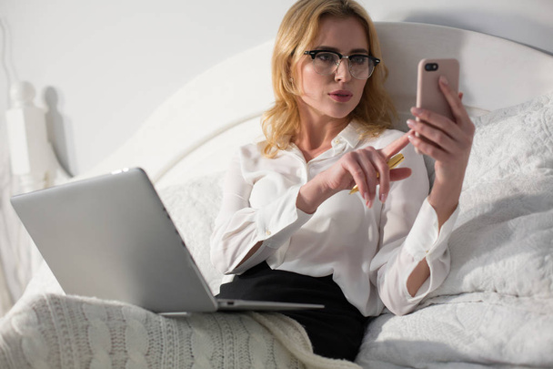 Businesswoman sitting in bed, using laptop - Foto, Imagem