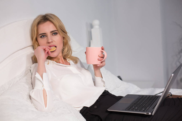 Business woman working on laptop and having a snack. - Photo, Image