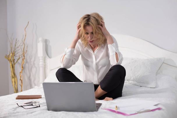 Business woman sitting on bed and working - Photo, image