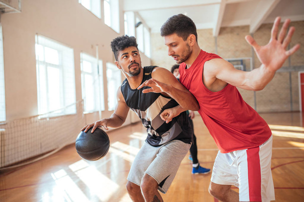 Two male friends playing a basketball together. - Foto, Bild