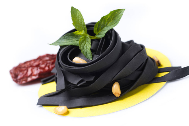 ungekochte schwarze Tagliatelle auf gastronomischer Plattenzusammensetzung - Foto, Bild