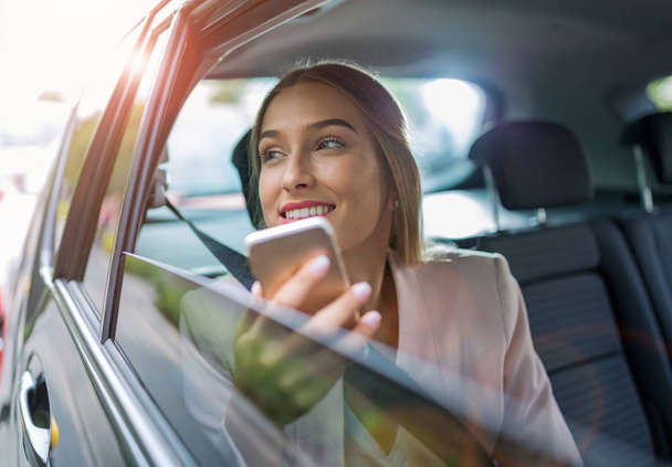 Woman with smart phone in a car - Foto, afbeelding