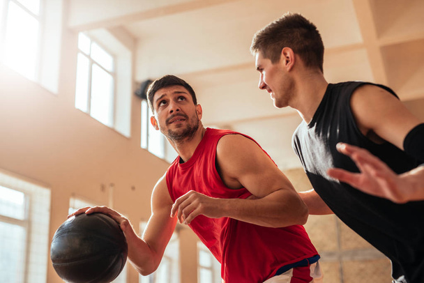 Shot of two basketball players playing basketball indoors. - 写真・画像