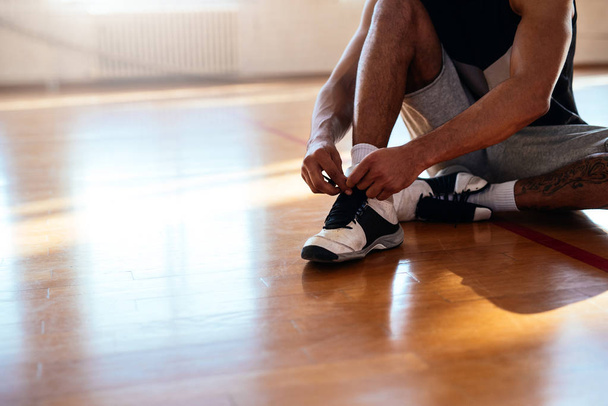 Portrait of a basketball player tying shoelaces. - Valokuva, kuva