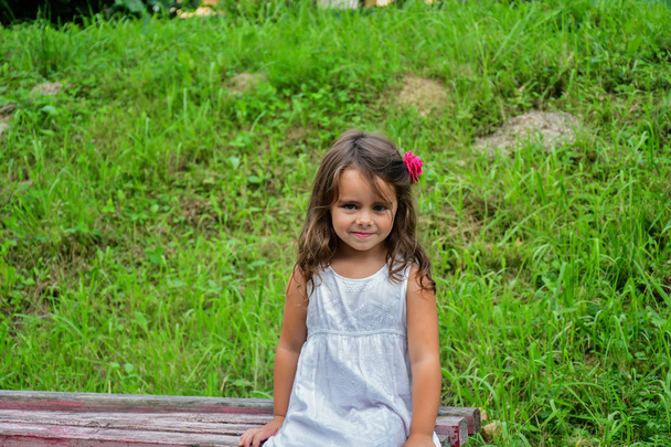 маленькая улыбающаяся девушка с цветком в волосах
  - Фото, изображение