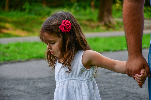 malá holčička drží za ruku s květinou ve vlasech - Fotografie, Obrázek