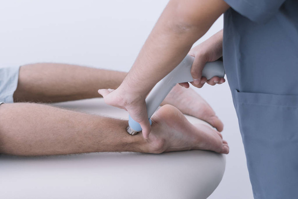 Le physiothérapeute traitant un homme utilisant un équipement pour la radiothérapie - Photo, image