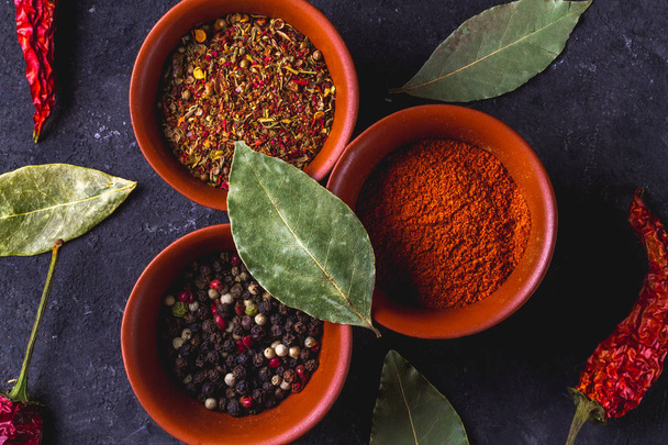 Top view of various spices, dried peppers and bay leaves on dark background.  - Valokuva, kuva
