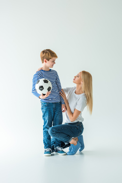 mère accroupi près de fils avec ballon de football sur blanc
 - Photo, image
