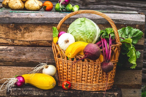 Fresh picked vegetables in wicker basket on wooden background. Vitamins. Healthy food concept. - Foto, Imagen