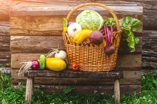Fresh picked vegetables in wicker basket on wooden background. Vitamins. Healthy food concept. - Fotografie, Obrázek