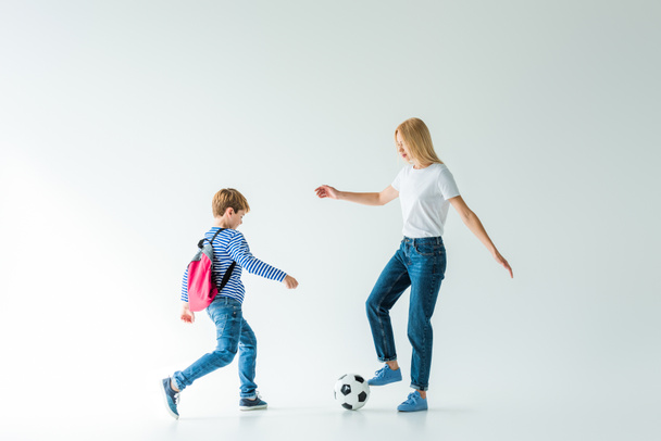 mother and son with backpack playing football on white - Photo, Image