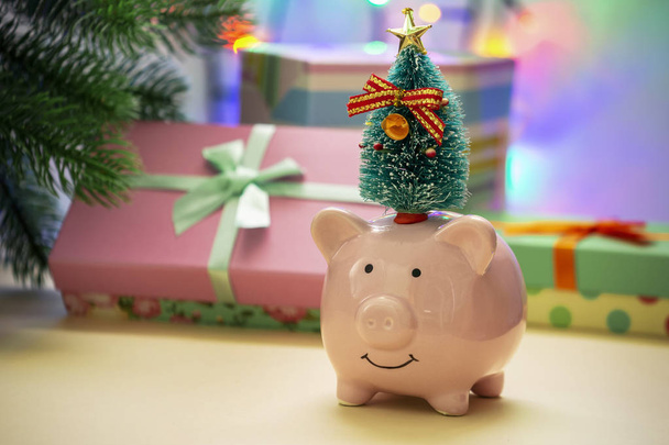 Um pequeno porquinho cerâmico com uma árvore de Natal. No fundo em um borrão de guirlanda de um Ano Novo e presentes. Símbolo do ano novo 2019. Cartão de Natal
. - Foto, Imagem
