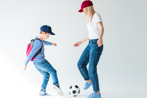 side view of mommy and son with backpack playing football on white - Фото, изображение