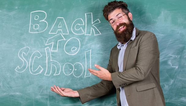 Welcome back. Teacher or educator welcomes students while stands near chalkboard with inscription back to school. Teacher begin first lesson after holidays. Invitation to celebrate knowledge day - Photo, image