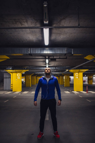 Handsome sportsman standing on a underground parking. - Φωτογραφία, εικόνα