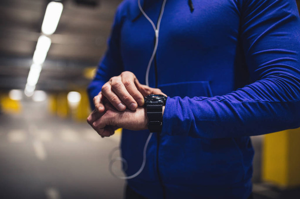 Shot of a young man setting the workout time on his smart watch. - Fotografie, Obrázek