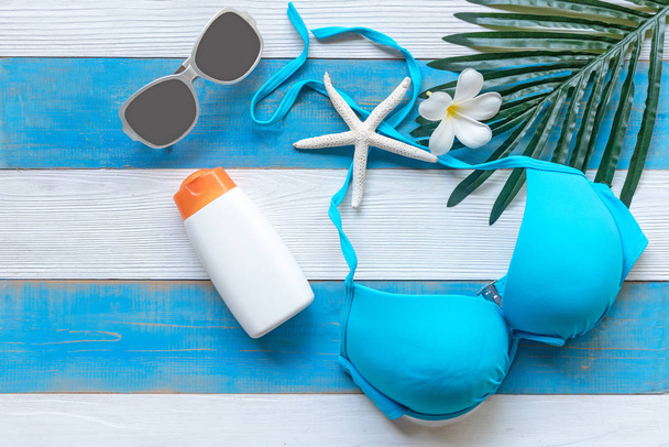 Summer Fashion woman blue swimsuit Bikini,  starfish, sunblock, sun glasses and spa flower.  Travel and vacations in the holiday, wood white and blue  background. Summer Concept. - Φωτογραφία, εικόνα