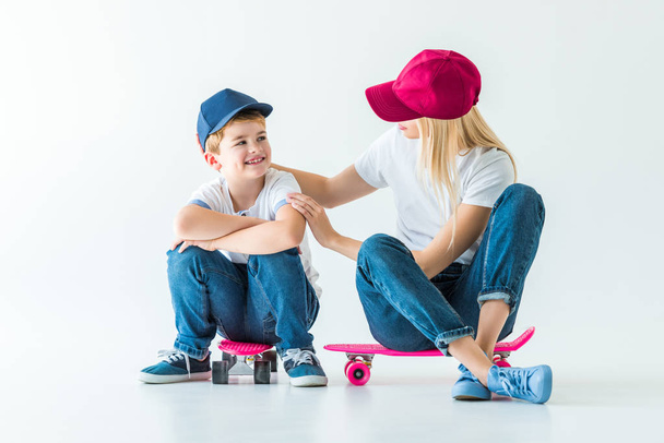 mother sitting on skate and hugging smiling son on white - Photo, Image