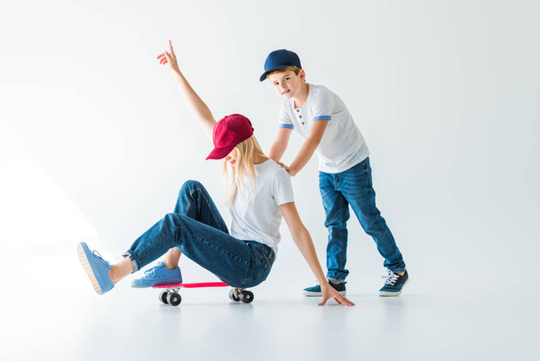 son pushing mother on skate on white, she showing one hand up - Photo, Image