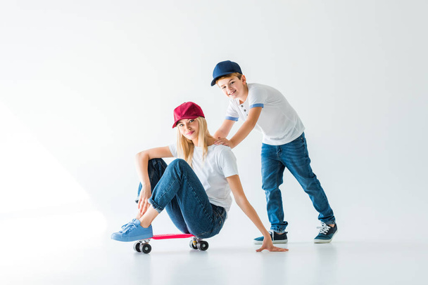 happy son pushing mother on skate on white - Фото, изображение
