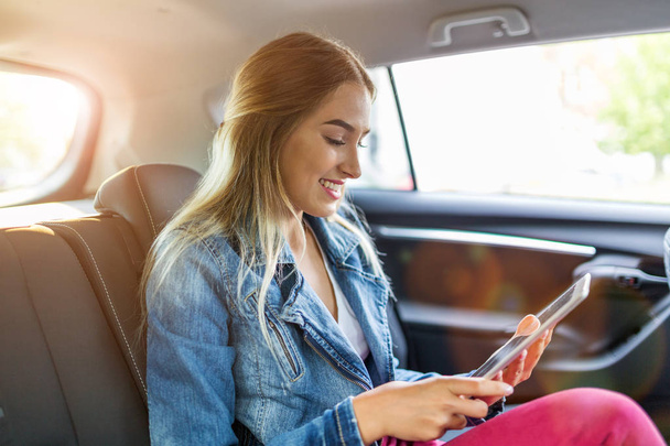 Νεαρή γυναίκα χρησιμοποιώντας ένα tablet σε ένα αυτοκίνητο - Φωτογραφία, εικόνα