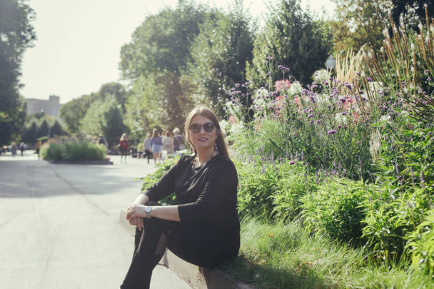 Portréja egy nő ül a fűben, a Városligetben a meleg napsütéses napon - Fotó, kép