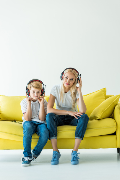 joyeuse mère et son fils écouter de la musique avec écouteurs sur canapé jaune sur blanc
 - Photo, image