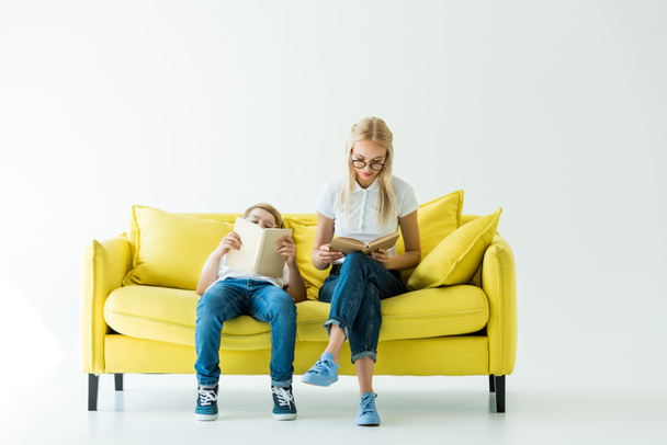 belle mère et adorable fils lisant des livres sur canapé jaune sur blanc
 - Photo, image