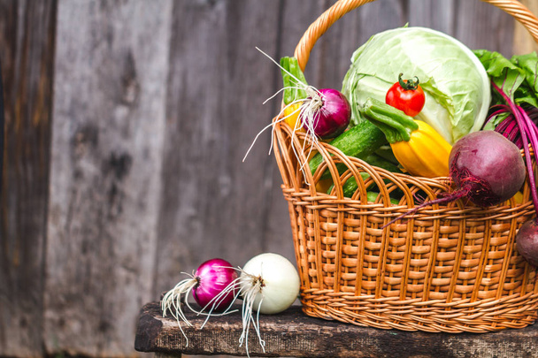 Fresh vegetables in basket on small chair on wooden background. - Foto, Imagen
